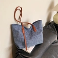 Bolso tote azul tejido con asas de cuero marrón sobre un sofá en un ambiente hogareño - Azul