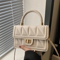 Chic cream quilted flap bag with woven handle and gold twist lock in soft natural light - White