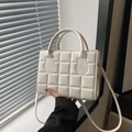 Elegant white quilted leather handbag with twin handles and crossbody strap in natural light - White