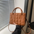 Brown quilted crossbody bag with top handle and adjustable strap in warm light - Brown