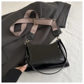 Detail of black patent leather shoulder bag with stylish woven strap and gold hardware - Black