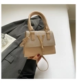 Beige textured leather tote bag with gold V-logo and fringe chain in a minimalist setting - Gold
