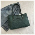 Close-up of dark green corduroy tote bag featuring vertical texture and gold studs - Green