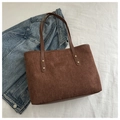 Detail of brown corduroy tote bag featuring a brand patch and sturdy gold rivets - Brown