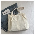 Detalle del bolso tote de nailon crema con textura plisada y etiqueta de moda - Blanco