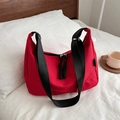 Minimalist red nylon shoulder bag with wide strap and double zipper on white bedding - Red