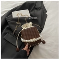 Detailed close-up of woven bucket bag with pearl handle and golden chain strap detail - Coffee