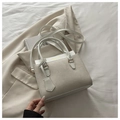 Detailed shot of white textured stitching bag on beige blazer with golden lettering - White