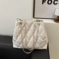 Elegant beige quilted bucket bag with golden chain strap and rhombus texture on black surface - White