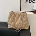 Elegant beige quilted bucket bag with gold chain straps on a stylish leather sofa - Khaki