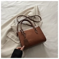 Detailed close-up of brown suede patchwork handbag with gold lettering on suit background - Dark Brown