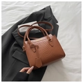 Detail of brown crocodile pattern handbag with gold fashion text on white fabric - Tan