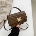 Brown quilted crossbody bag with gold heart buckle held by a model in a blazer - Brown
