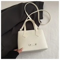 Detail of elegant cream leather handbag with fashion metal logo on white texture - White