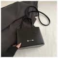 Detail of black faux leather tote bag with metal Fashion logo and slim shoulder strap - Black