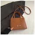 Detail of a brown leather square handbag with FASHION silver metal plate and shoulder strap - Tan