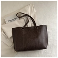 Detail of dark brown vintage faux leather tote with embossed Fashion logo and oily texture - Coffee