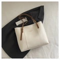 Detail of minimalist cream tote bag showing adjustable brown strap and golden buckle - White