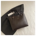 Close-up of golden logo and hardware on dark brown leather tote bag with shoulder straps - Coffee