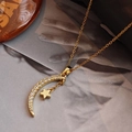 Elegante collar dorado con colgante de estrella y luna con circonitas sobre fondo de revista - Dorado