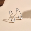 Détail des boucles d'oreilles épingles à nourrice en argent avec une finition polie sur beige - Boucles d'Oreilles Clous Épingle de Nourrice Or Blanc
