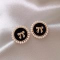 Vue macro de boucles d'oreilles vintage avec centre noir, nœud doré et bordure en perles - Boucles d'Oreilles Clous Noeud Noir
