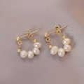 Détails de boucles d'oreilles dorées avec perles d'eau douce sur tissu violet - Boucles d'Oreilles Clous Perle Française