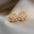 Vue macro de boucles d'oreilles fleurs dorées avec zircons sur satin de champagne - Boucles d'oreilles clous fleur en spirale