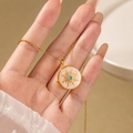Golden oval locket necklace with sunburst texture and turquoise stone held by hand - Round Sun Locket / White