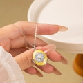 Detail of vintage oval flower locket necklace with yellow enamel and small pearl inlay - Oval Flower Locket / Yellow