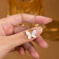 Primo piano della collana a farfalla dorata con ali iridescenti e centro in zircone - Collana Farfalla Oro