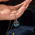 Macro detail of silver fishtail pendant with blue gemstone held in hand over jewelry box - Fish Tail Style / Silver-Blue