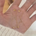 Elegante gouden vlinder doortrekoorbellen met lang kettingontwerp getoond op de hand - Goud