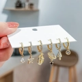 Close-up of gold hoop earrings set with hollow star, moon, and zircon-studded astronaut charms - Rocket Planet Gold Set
