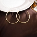 Close-up of large gold C-shaped hoop earrings on elegant brown satin with a textured finish - 40mm / Gold