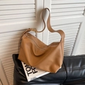 Braune Vintage-Hobo-Tasche mit Lychee-Struktur auf einem schwarzen Ledersofa platziert - Khaki