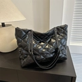 Quilted black leather tote bag with silver chain straps shown in a minimalist interior - Black