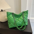 Vibrant green quilted tote bag with silver chain strap on a dark wooden surface - Green
