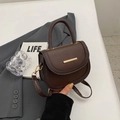 Dark brown pebbled leather saddle bag with gold metal trim and top handle for women - Coffee