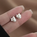 Elegante zilveren strik oorknopjes met witte parels gepresenteerd in een lifestyle-opname - Schroefknopjes / Zilveren Strik Parel Oorknopjes