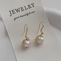 Macro view of gold bow pearl earrings with irregular textured metal on display - Irregular Pearl Gold