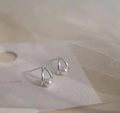 Detail of silver bow pearl earrings featuring polished metal curves and lustrous white pearls - Hollow Pearl Platinum