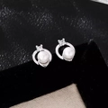 Macro shot of silver bow pearl earrings with a clear zircon on black velvet background - Hoop Earrings Platinum