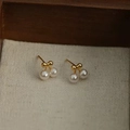 Detailed view of French-style bow and pearl cherry-shaped earrings on textured fabric - Cherry Pearl