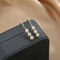 Macro detail of drop earrings featuring gold bars with pavé zircons and dangling white pearls - Double Pearl Drop Earrings