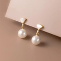 Elegant gold bow earrings with white shell fans and lustrous pearls on a pink stand - Luxury Pearl Earrings