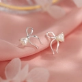 Macro shot of silver bow stud earrings with heart-shaped pearl on pink silk background - Heart Bow-Silver