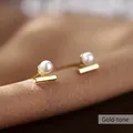 Detailed close-up of a gold pearl stud earring on a soft silk fabric background - Line Pearl-Gold