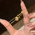 Elegante gouden armband met zwevende bal, micro-pave diamanten en een fonkelende steen - Gouden zwevende bal armband