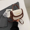 Mini cream leather saddle bag with brown trim and gold bar detail in a lifestyle setting - Off White